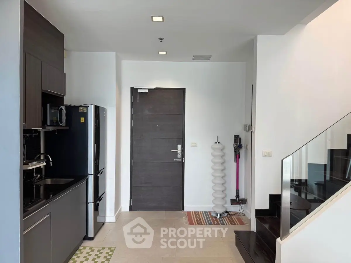 Modern kitchen with sleek appliances and stylish staircase in a contemporary home.