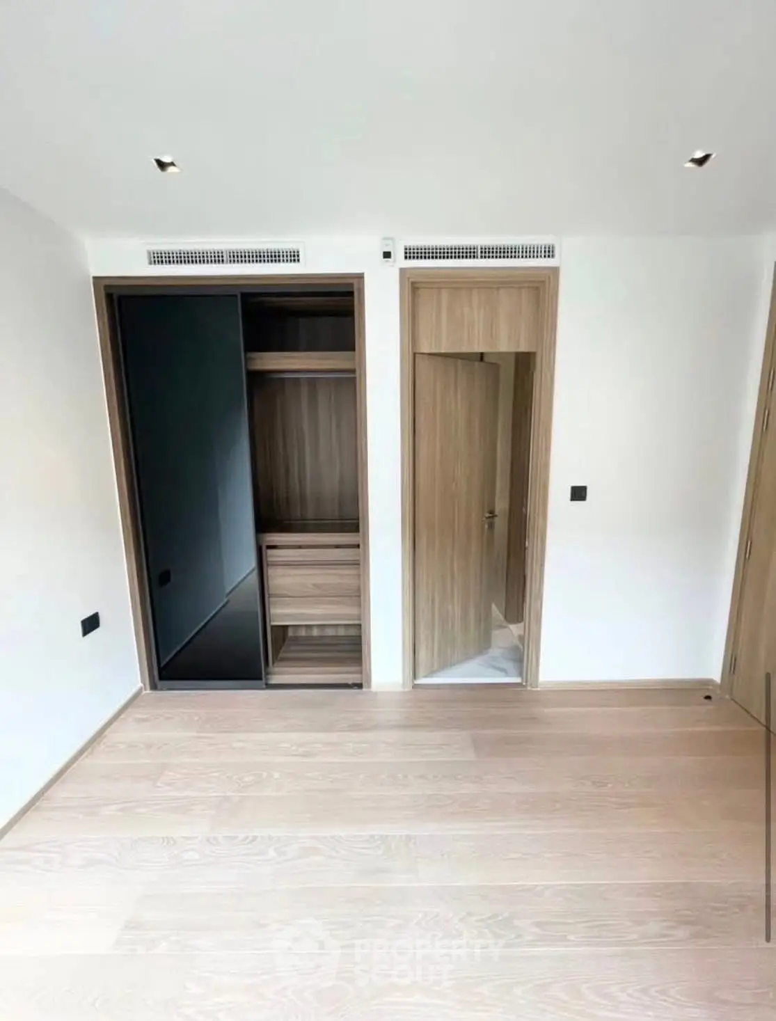 Spacious modern bedroom with built-in wooden wardrobe and sleek design.