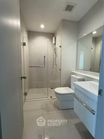 Modern bathroom with glass shower and sleek fixtures in contemporary apartment.