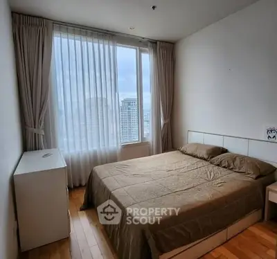 Cozy bedroom with city view and natural light, featuring a comfortable bed and minimalist decor.