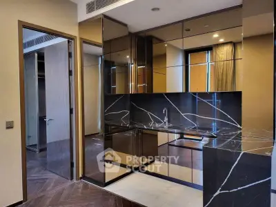 Luxurious modern kitchen with sleek black marble countertops and mirrored cabinets.