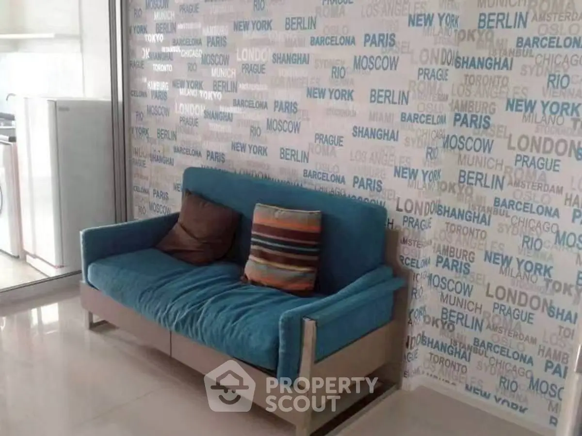 Modern living room with blue sofa and city-themed wallpaper, bright and inviting space.