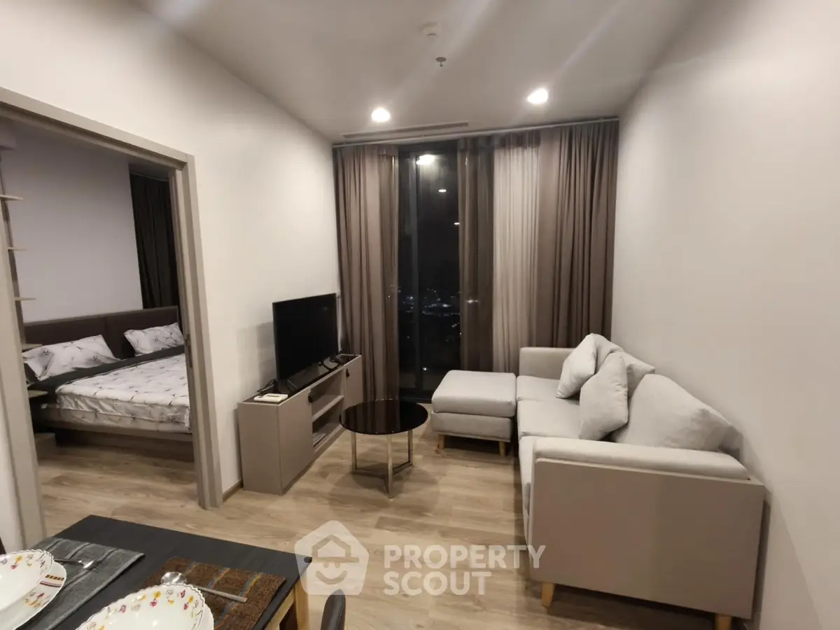 Modern living room with cozy sofa and city view, adjacent to stylish bedroom in open layout apartment.