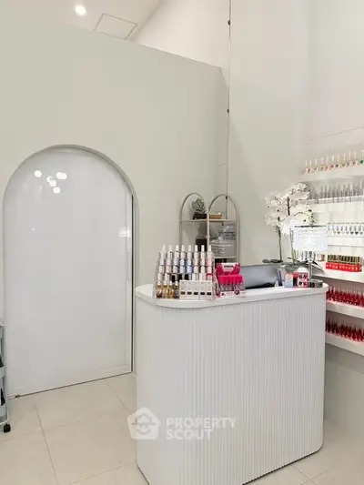 Modern nail salon interior with sleek white reception desk and organized nail polish display.