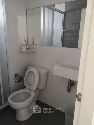 Modern bathroom with sleek fixtures and a minimalist design, featuring a shower and compact sink.