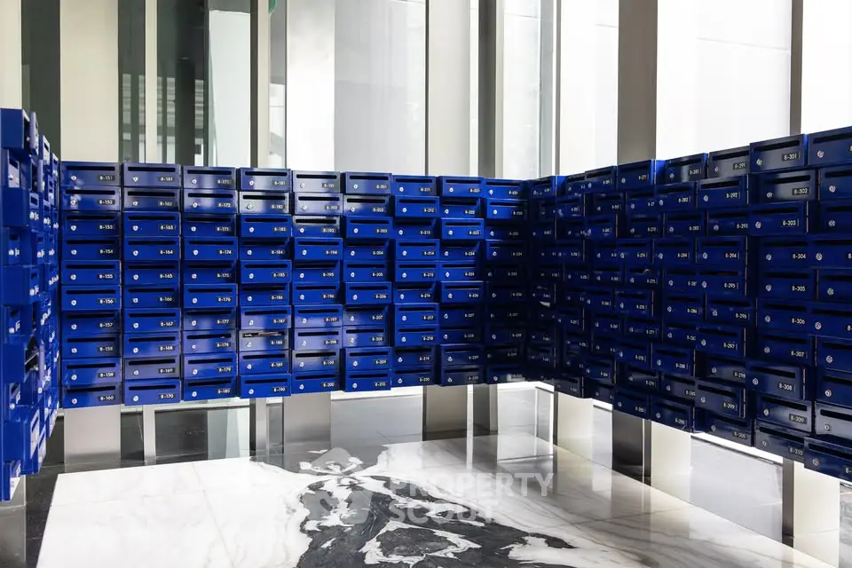 Modern building lobby with sleek blue mailboxes and marble flooring.