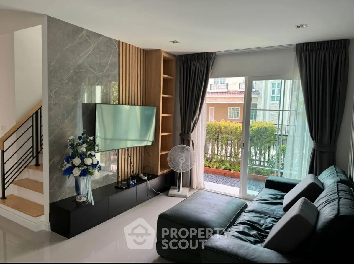 Modern living room with sleek design, large TV, and cozy sectional sofa overlooking a garden view.