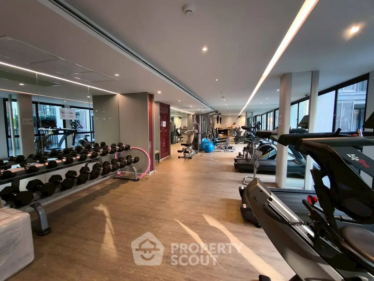 Spacious modern gym with state-of-the-art equipment and large windows for natural light.