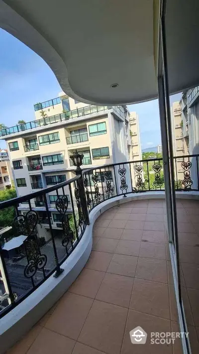 Spacious balcony with elegant wrought iron railing and scenic view of modern residential buildings.