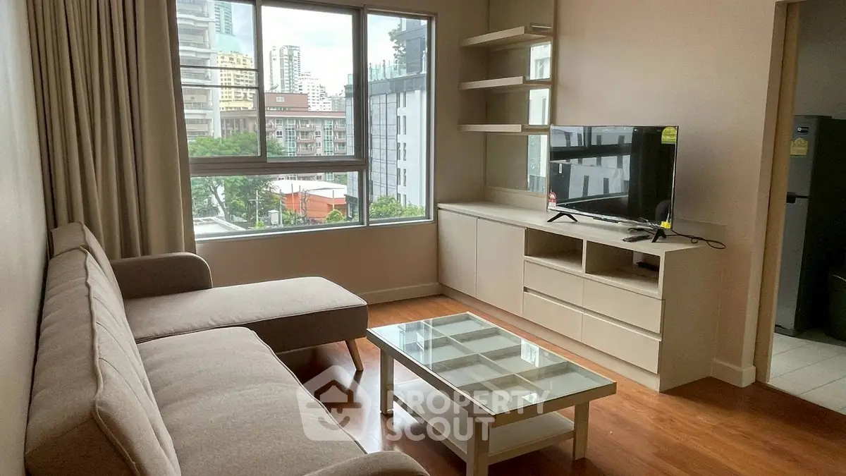 Modern living room with city view, featuring cozy sofa and sleek TV unit.