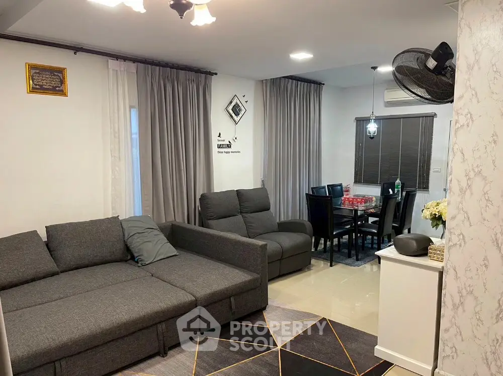Modern living room with stylish gray sofa and dining area, perfect for family gatherings.