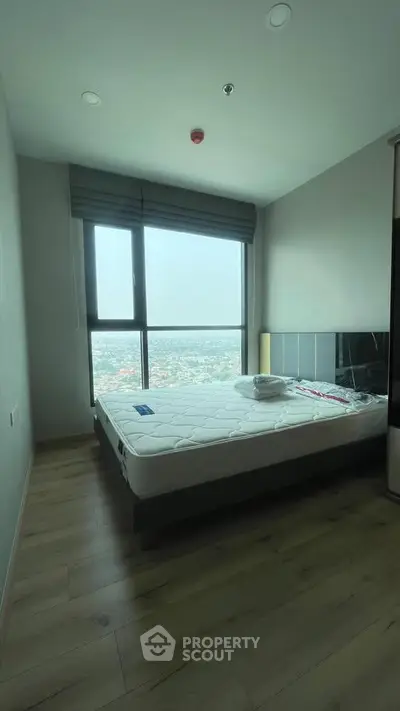 Modern bedroom with large window offering stunning city view, featuring sleek design and natural light.