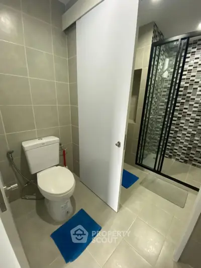 Modern bathroom with sleek shower and tiled walls in contemporary apartment.