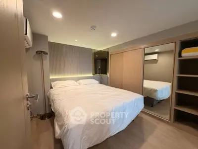 Modern bedroom with cozy lighting and mirrored wardrobe in a stylish apartment.