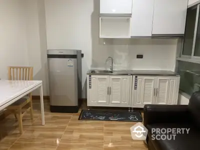 Modern kitchen with sleek cabinetry, stainless steel fridge, and cozy dining area in a bright, open layout.