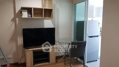 Cozy living room with modern TV setup and glass dining table near kitchen
