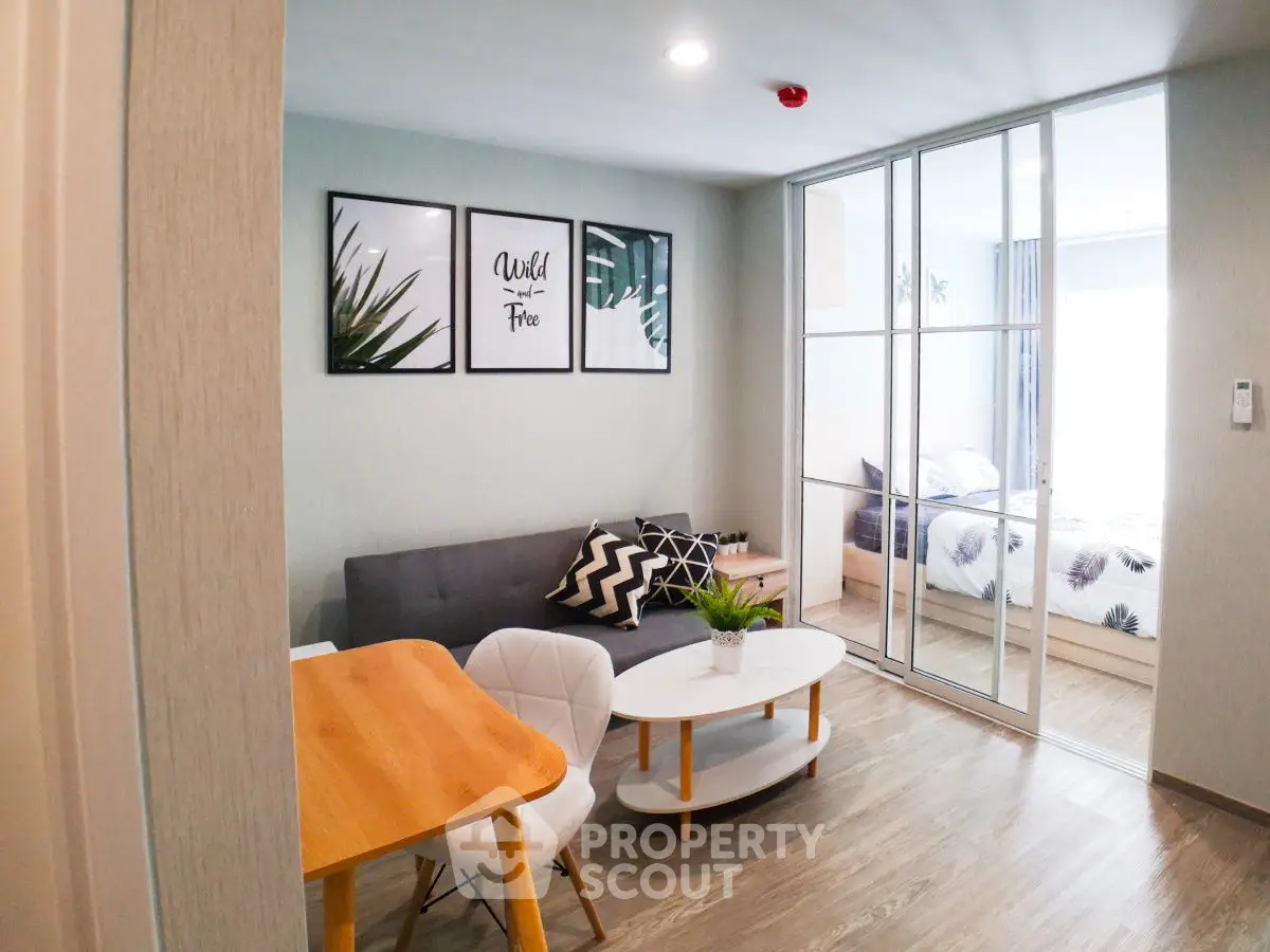 Modern open-plan living room with stylish decor and sliding glass doors to bedroom.