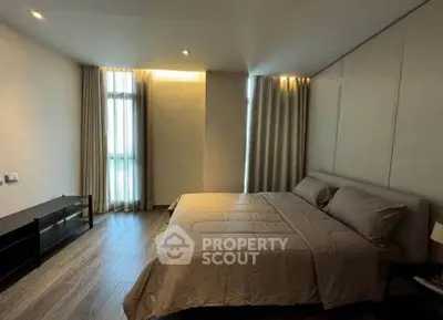 Spacious modern bedroom with elegant decor and large windows for natural light.