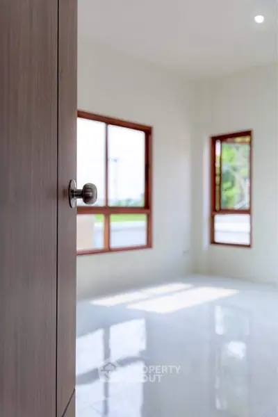 Bright empty room with large windows and glossy floor, ideal for customization.