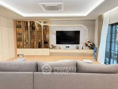 Luxurious living room with modern decor, large TV, and elegant display cabinet, perfect for relaxation and entertainment.