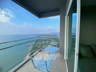 Stunning balcony with panoramic ocean view and cozy seating area.