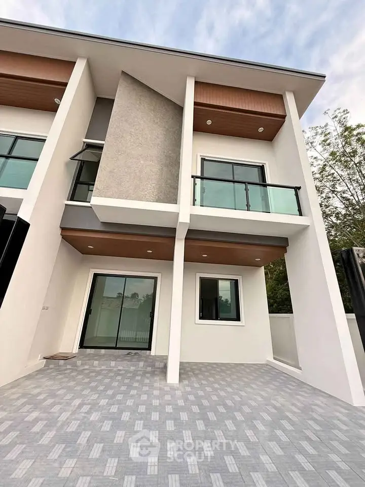 Modern two-story house with sleek design and glass balcony, perfect for contemporary living.