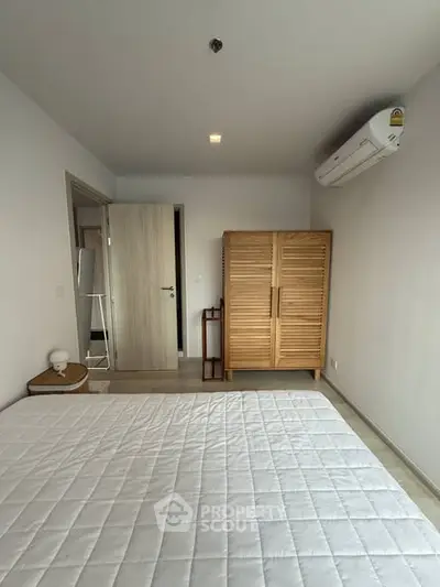 Spacious bedroom with modern air conditioning and wooden wardrobe, perfect for comfort and style.