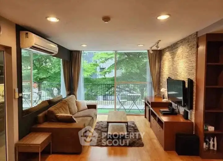 Spacious living room with modern decor and large windows overlooking greenery.