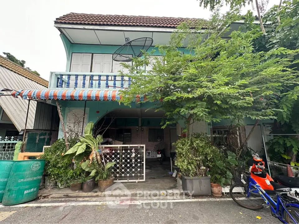 Charming two-story house with lush greenery and a cozy balcony, perfect for family living.