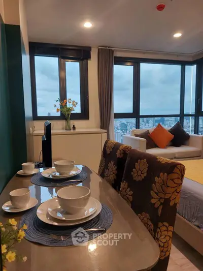 Modern living room with city view, stylish dining setup, and cozy seating area.