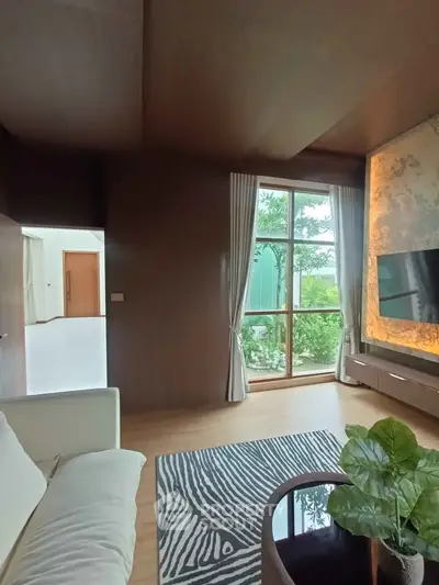 Luxurious living room with large window and elegant decor, offering a serene garden view.