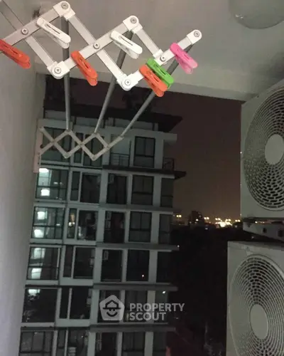 Modern apartment balcony with city view and air conditioning units at night.