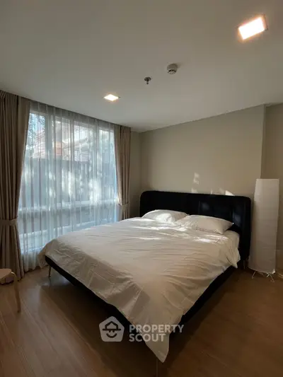 Spacious bedroom with large window and modern decor, perfect for relaxation and comfort.