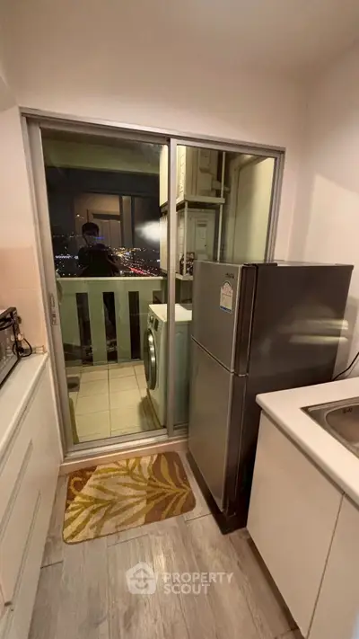 Compact kitchen with balcony view, featuring modern appliances and sleek design.