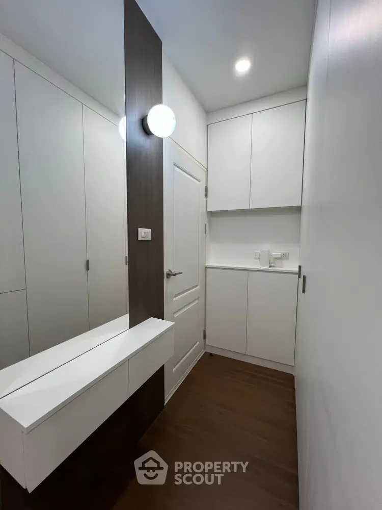 Modern minimalist storage room with sleek white cabinets and wooden flooring