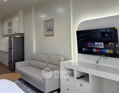 Modern living room with sleek design, featuring a wall-mounted TV, cozy sofa, and stylish kitchen area.
