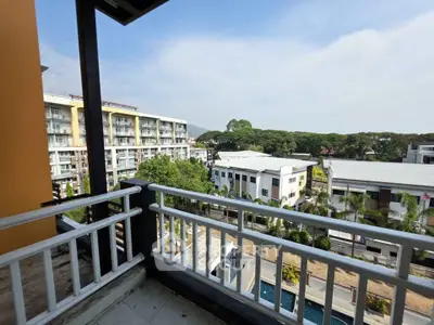 Spacious balcony with scenic view of modern buildings and lush greenery.