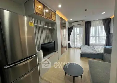 Modern studio apartment with sleek kitchen and cozy living area, featuring large windows and stylish decor.