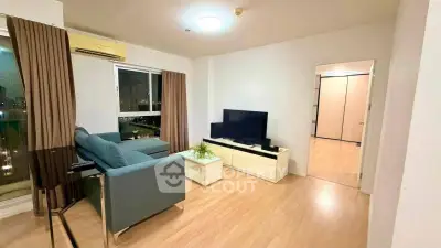 Modern living room with city view, featuring sleek furniture and a large TV, perfect for relaxation.