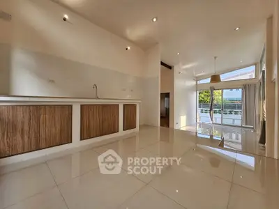 Spacious modern living room with open kitchen and large windows offering natural light.
