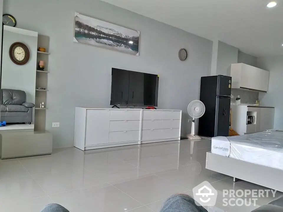 Spacious modern living room with sleek furniture and large TV, perfect for relaxation.