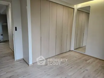 Spacious modern room with sleek wooden flooring and built-in wardrobe
