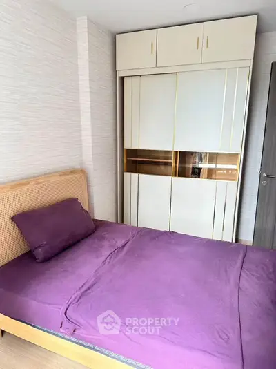 Modern bedroom with stylish wardrobe and purple bedding in a cozy apartment.