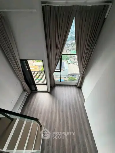 Spacious loft with floor-to-ceiling windows and balcony offering stunning city views.