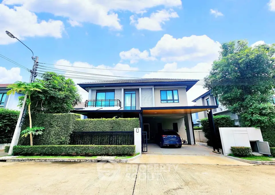 Modern two-story house with carport and lush greenery in a serene neighborhood.