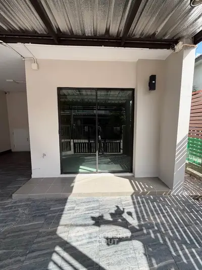 Modern patio with sliding glass doors and covered roof, perfect for outdoor relaxation.