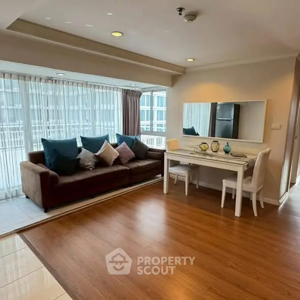 Spacious living room with large windows and modern decor in a high-rise apartment.