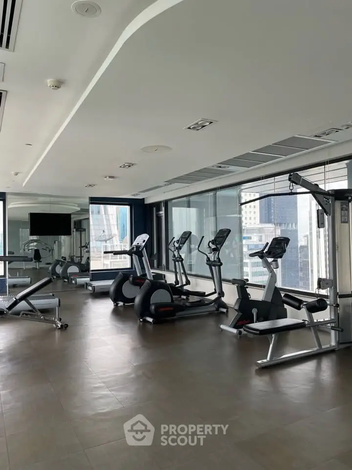 Modern gym with state-of-the-art equipment and city view in luxury building.