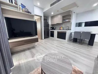 Modern open-layout living room with sleek kitchen and dining area, featuring contemporary furniture and stylish decor.