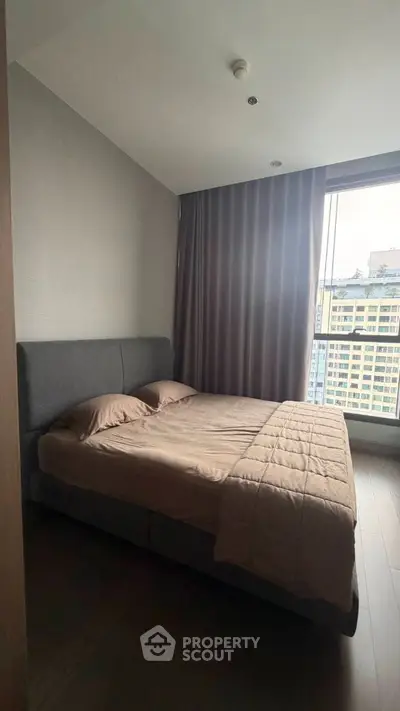 Cozy bedroom with large window offering city view, featuring a comfortable bed and modern decor.